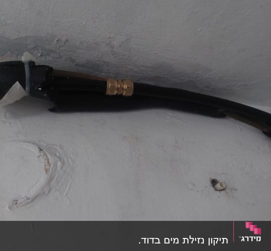 צינור שחור עם מחבר מתכת על קיר לבן